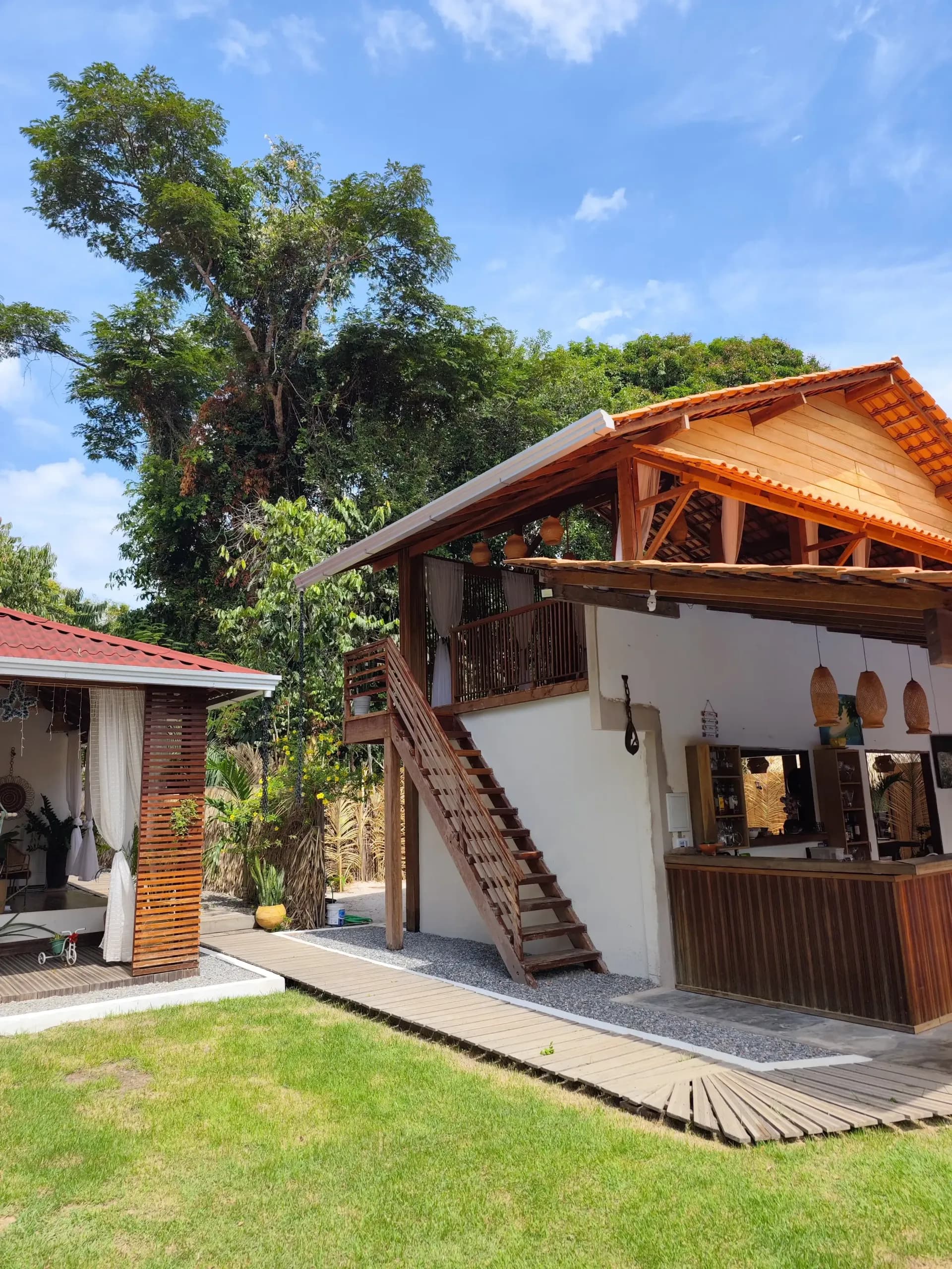 Bar de madeira com luminárias de fibra e escada externa que leva ao deck superior